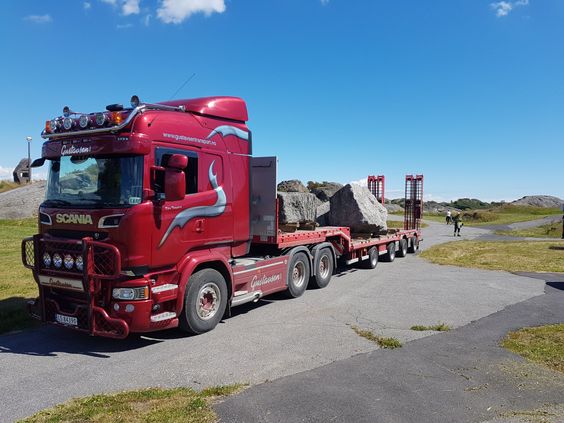 Rød trailer på viddene med transport av steinblokker