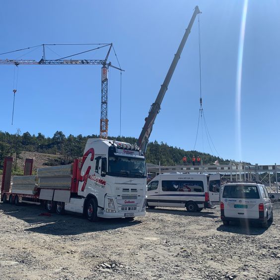 Hvit lastebil som transport av elementer på byggeplass